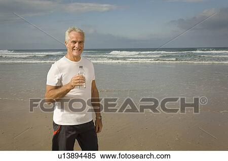 Male drinking water on a beach View Large Photo Image Stock Photography - Male drinking water on a beach. Fotosearch