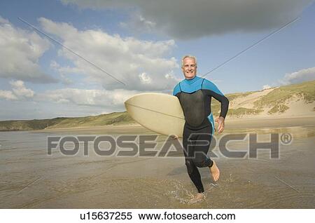 Male running into sea with a surfboard View Large Photo Image Stock Photography - Male running into sea with a surfboard. Fotosearch
