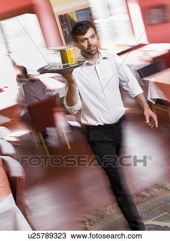 Stock Image - Male waiter with drinks in hand. Fotosearch