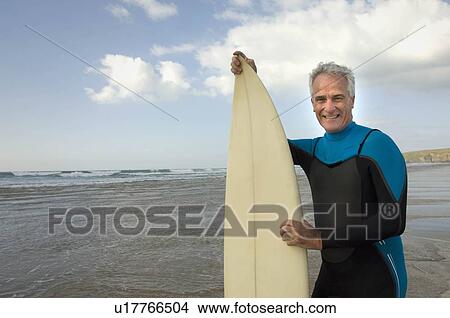 Picture - Male with surfboard on a beach. Fotosearch