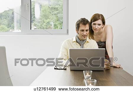 Stock Photo - Man and woman looking at laptop computer. Fotosearch
