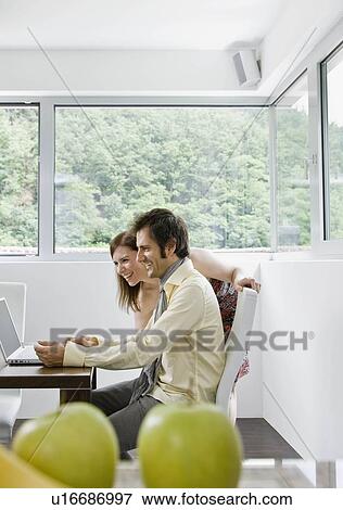 Stock Photo - Man and woman looking at laptop computer. Fotosearch
