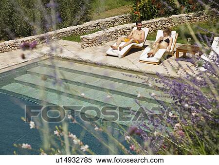 Stock Photography - Man and woman relaxing by the pool. Fotosearch
