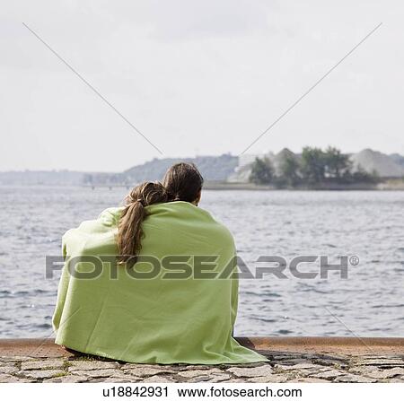Stock Image - Man and woman stare out at a lake. Fotosearch