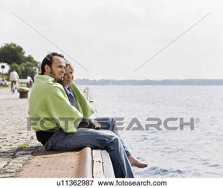 Stock Photo - Man and woman stare out at a lake. Fotosearch