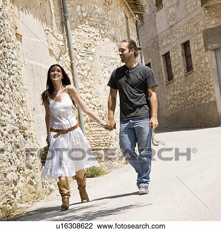 Stock Image - Man and woman walking and holding hands. Fotosearch