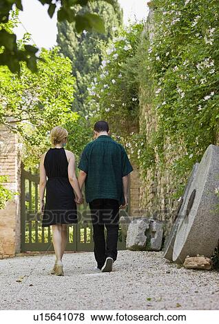 Stock Photo - Man and woman walking and holding hands. Fotosearch