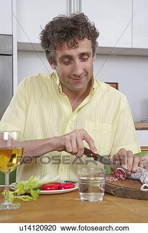 Man at home cutting salami View Large Photo Image Stock Image - Man at home cutting salami. Fotosearch