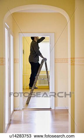 Stock Image - Man changing a light-bulb on a ladder. Fotosearch