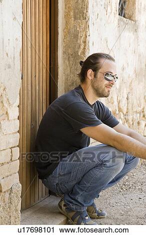 Man crouch down by a doorway View Large Photo Image Stock Image - Man crouch down by a doorway. Fotosearch