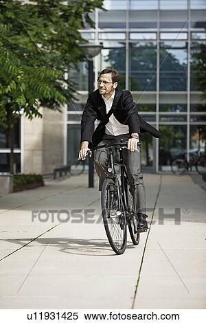 Stock Photography - Man leaving the office on bicycle. Fotosearch