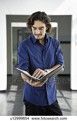 Man looking at a file View Large Photo Image Picture - Man looking at a file. Fotosearch
