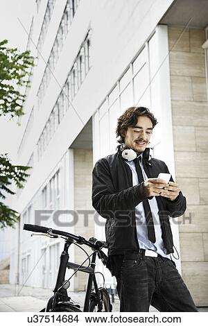 Picture - Man next to bicycle, headphones on. Fotosearch