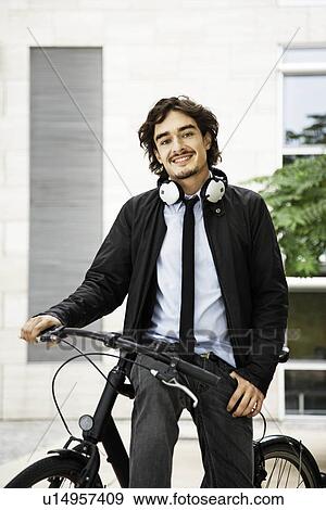 Stock Photo - Man on a bicycle, headphones on. Fotosearch