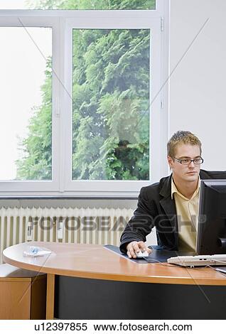 Stock Photography - Man on computer in office. Fotosearch