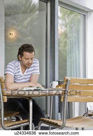 Stock Photograph - Man reading and eating a meal. Fotosearch