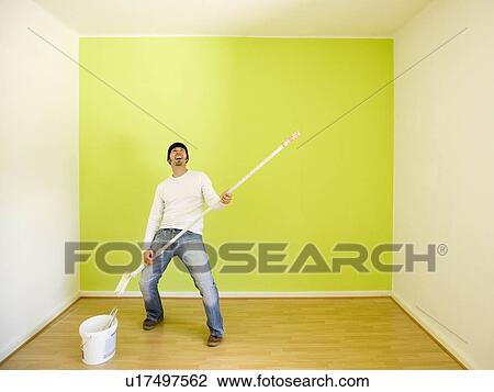 Stock Image - Man rocking while painting a room. Fotosearch