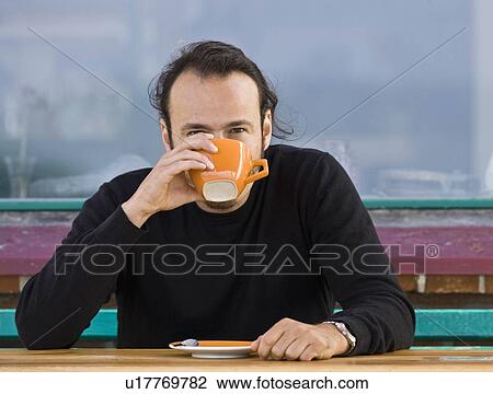Stock Image - Man sitting at a cafe drinking coffee. Fotosearch