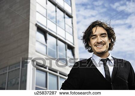 Stock Photo - Man smiling at camera, building behind. Fotosearch
