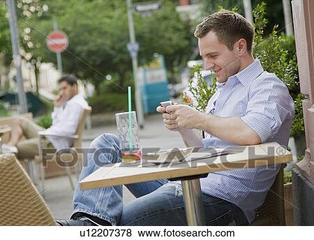 Stock Photo - Man text messaging at table. Fotosearch