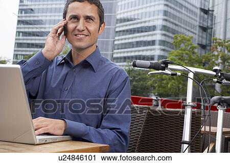 Stock Image - Man working on laptop outside. Fotosearch