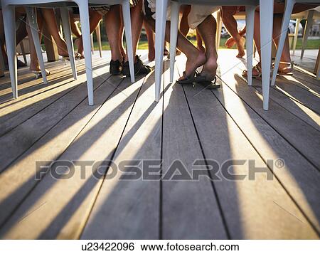 Stock Photograph - Many legs under table casting shadows. Fotosearch