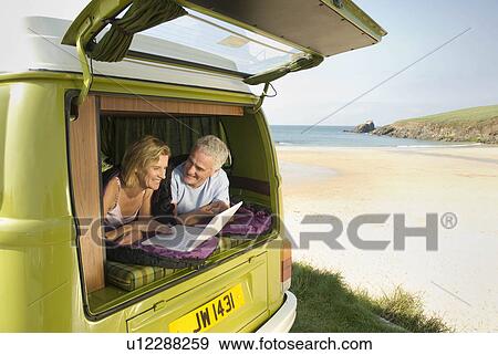 Stock Photo - Mature couple lying in camper van. Fotosearch