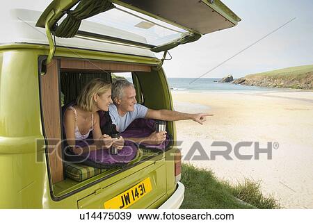 Stock Photo - Mature couple lying in camper van. Fotosearch
