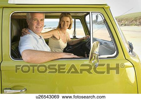 Stock Photo - Mature couple sat in camper van. Fotosearch