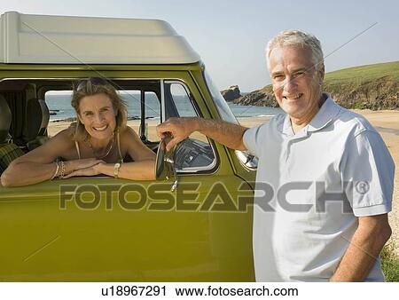 Stock Image - Mature couple with vintage camper van. Fotosearch
