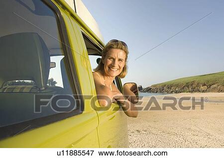 Stock Photo - Mature female sat in camper van. Fotosearch