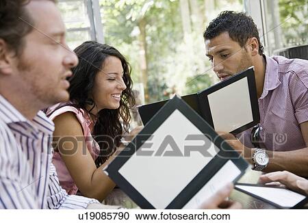 Stock Image - Men and women talking over menus. Fotosearch