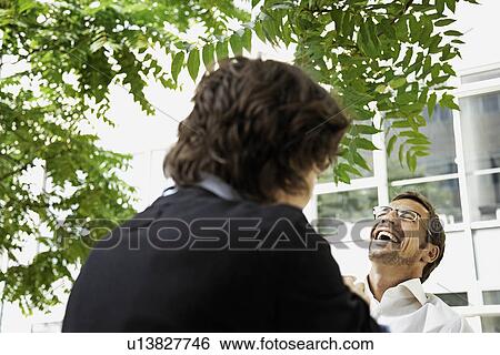 Stock Photograph - Men having a laugh, outside. Fotosearch