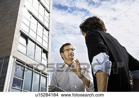 Picture - Men talking, holding a newspaper. Fotosearch