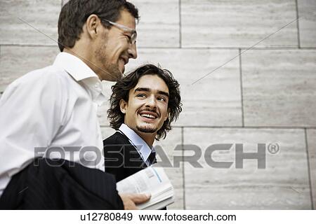 Stock Photo - Men talking, holding a newspaper. Fotosearch