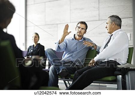 Picture - Men talking in waiting room. Fotosearch
