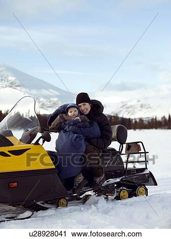 Stock Image - Mother and baby on Snowmobile. Fotosearch