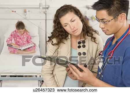 Stock Image - Mum checks daughters notes with a doctor. Fotosearch