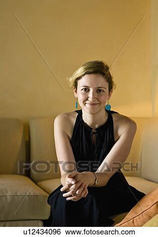 Stock Photograph - Portrait of a woman sitting on a couch. Fotosearch