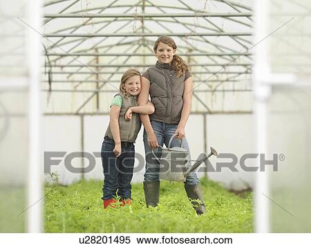 Stock Photography - Sisters With Watering Can In Polytunnel. Fotosearch