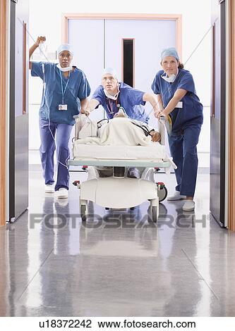 Three doctors pushing a patient in bed View Large Photo Image Stock Image - Three doctors pushing a patient in bed. Fotosearch