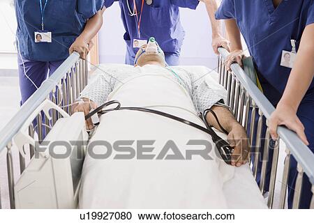 Three doctors pushing a patient in bed View Large Photo Image Stock Image - Three doctors pushing a patient in bed. Fotosearch