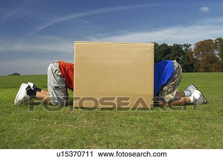 Stock Image - two boys crawling into box. Fotosearch