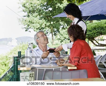 Stock Image - Waitress bringing the bill to the table. Fotosearch