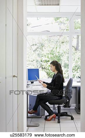 Stock Photo - Woman at desk in office. Fotosearch