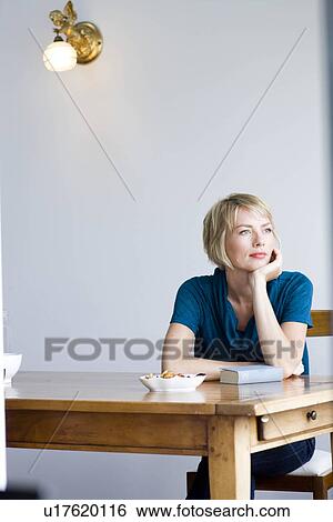 Woman at table looking into distance View Large Photo Image Stock Photograph - Woman at table looking into distance. Fotosearch