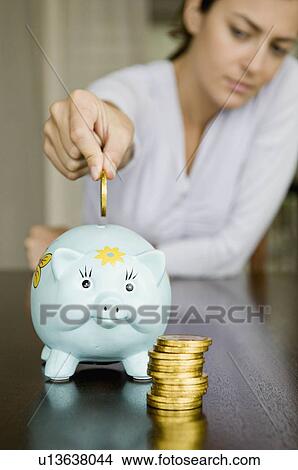 Woman dropping money into a piggy bank. View Large Photo Image Picture - Woman dropping money into a piggy bank.. Fotosearch