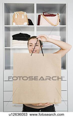 Stock Image - Woman holding up a shopping bag.. Fotosearch