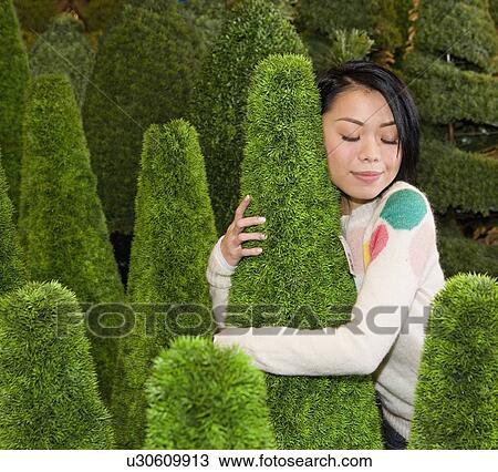 Stock Image - Woman hugging shrub. Fotosearch