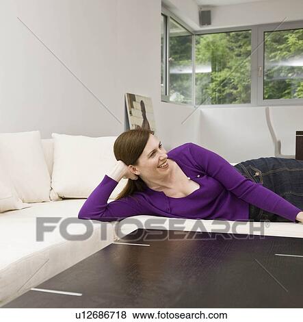 Stock Photo - Woman laying on the couch. Fotosearch